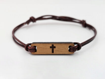 Ein christliches Armband mit hellem Holz. Graviert mit einem Kreuz.