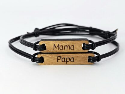 Zwei handgefertigte, personalisierbare Holzarmbänder in Kirsch- und Nussbaumholz mit individuellen Gravuren. Ein Armband trägt die Gravur "Papa", das andere "Mama".