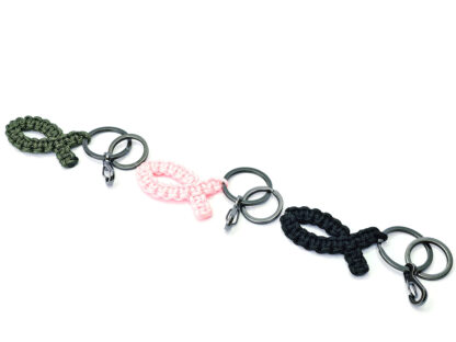 Übersicht aller drei Ichthys-Credo Fisch Schlüsselanhänger aus Paracord in den Farben Rosa, Schwarz und Navygrün nebeneinander auf hellem Hintergrund.
